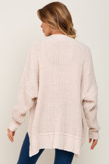 Back view of a woman wearing an oversized cream chunky knit cardigan sweater with ribbed cuffs and hem