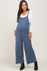 woman wearing a blue maternity jumpsuit with a white long sleeve top and a visible baby bump