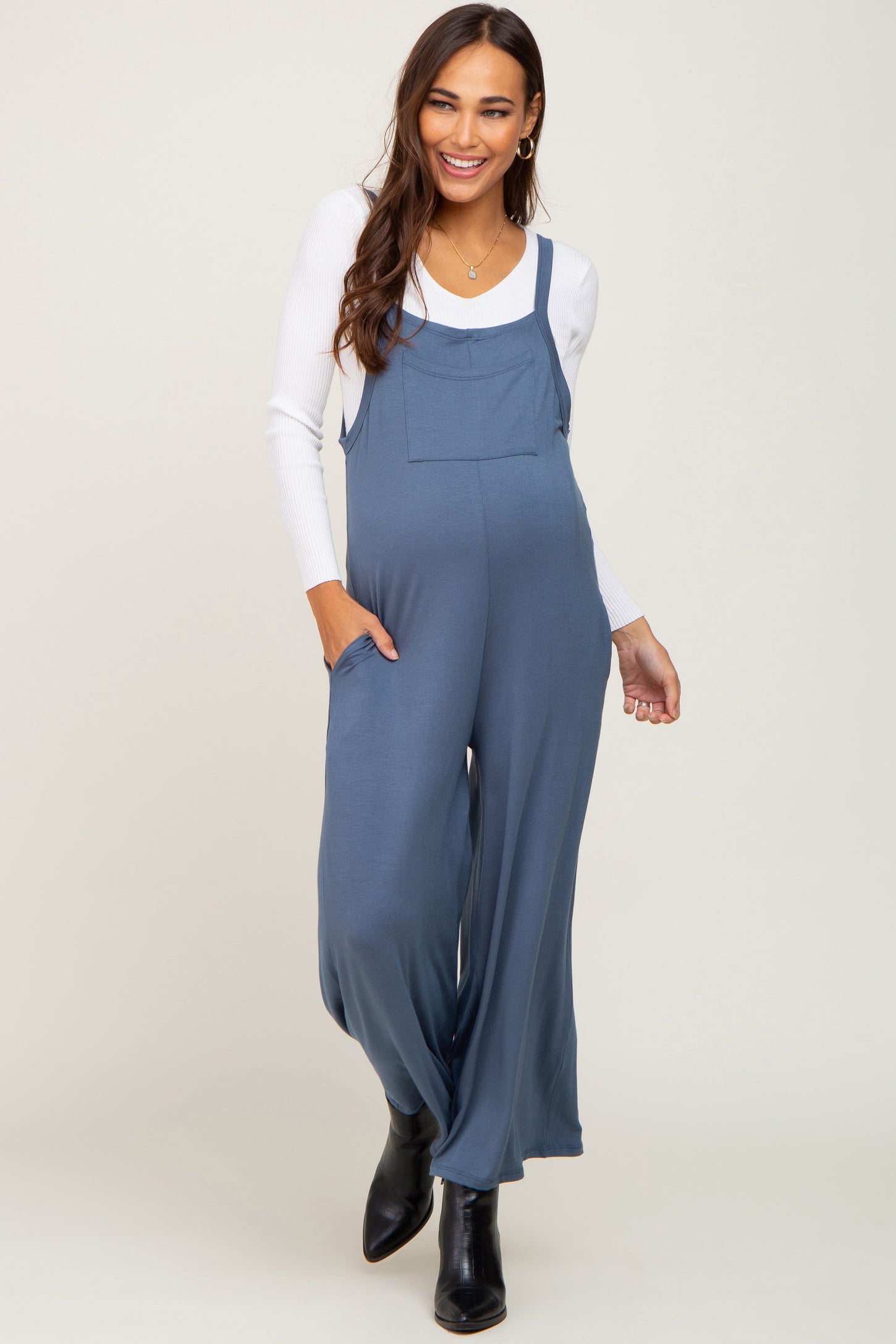 woman wearing a navy blue maternity jumpsuit with loose legs and pockets, showcasing her baby bump