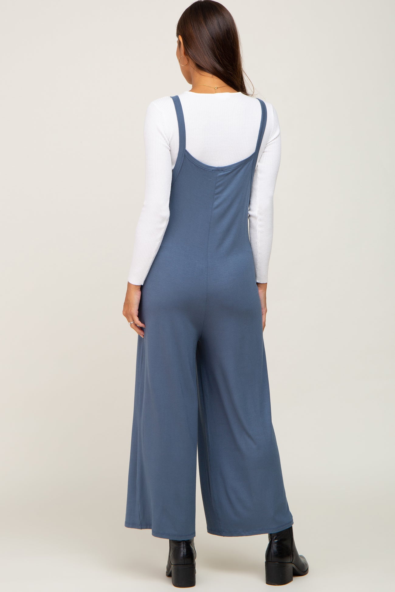 woman wearing a blue maternity jumpsuit with wide legs, seen from the back