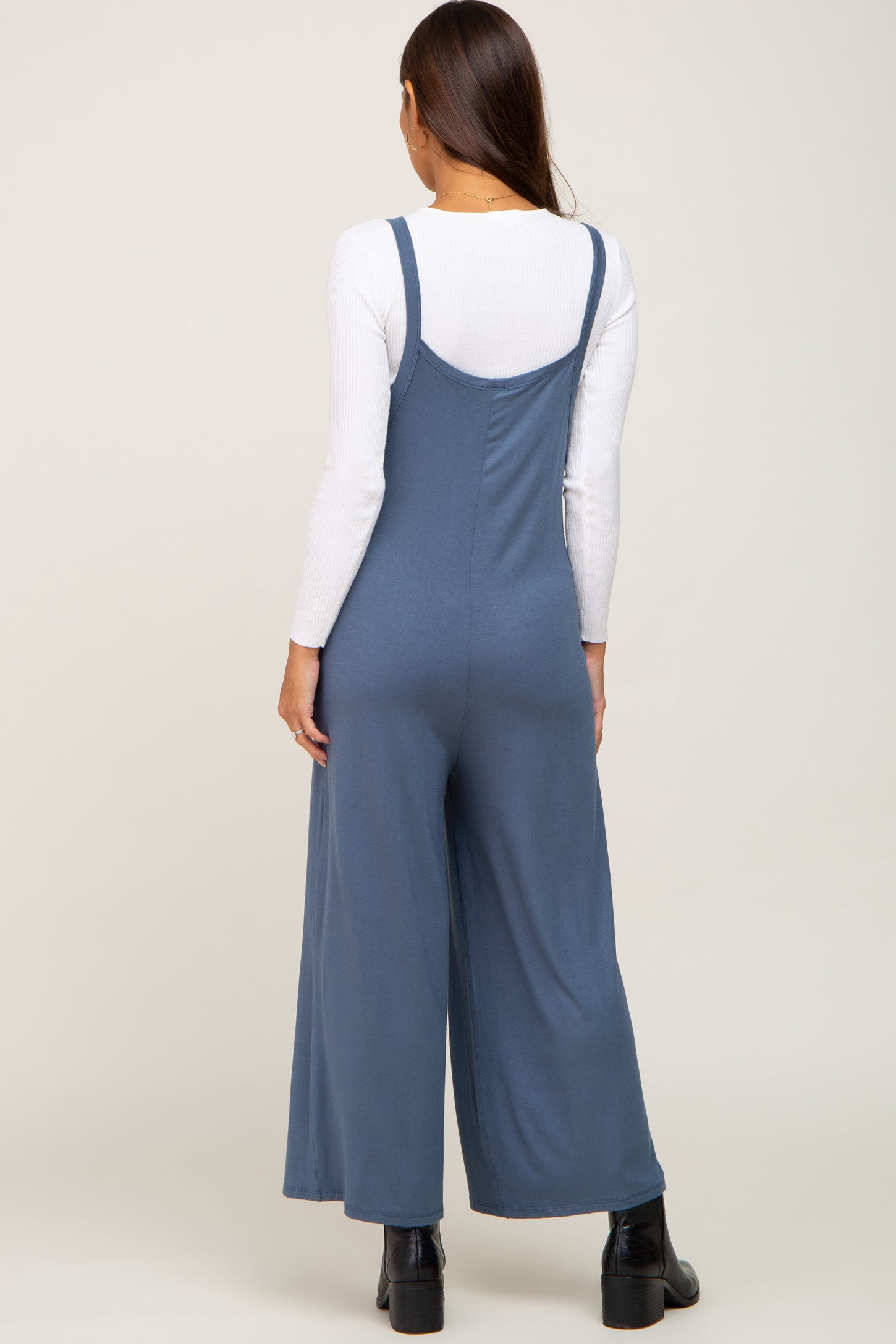 woman wearing a blue maternity jumpsuit with wide legs, seen from the back
