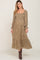 woman wearing olive green floral smocked maternity midi dress with long sleeves and brown boots