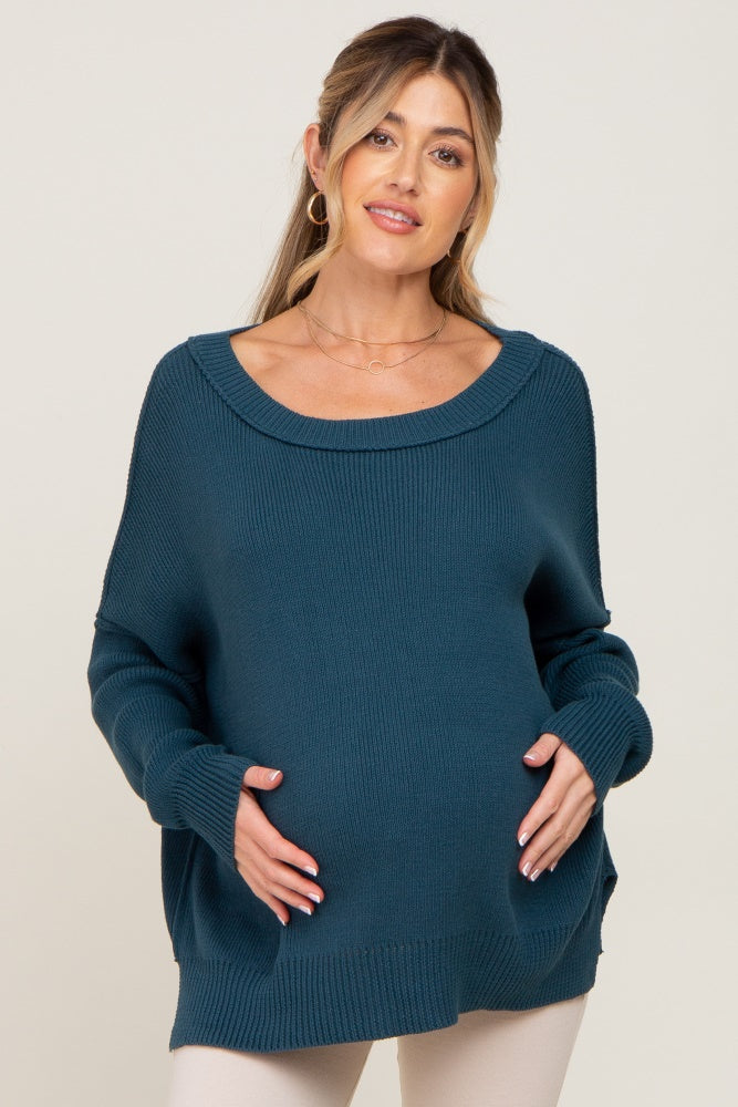 woman wearing a teal maternity sweater with a relaxed fit and holding her baby bump