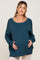 woman wearing a teal maternity sweater with a relaxed fit and holding her baby bump