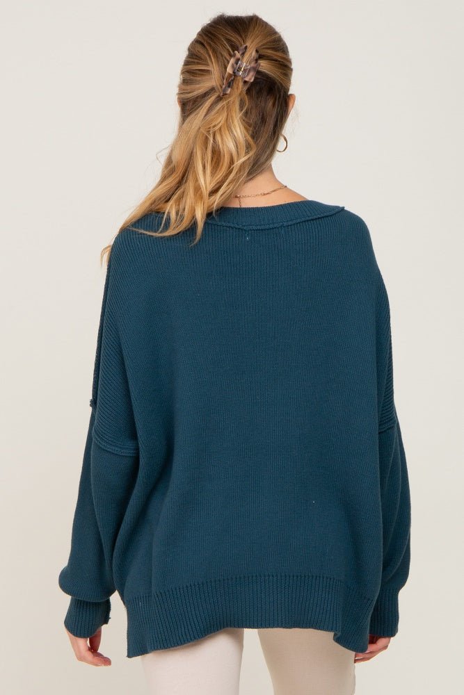 woman wearing a teal oversized maternity sweater with a relaxed fit and dropped shoulders, viewed from the back