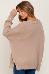 woman wearing a beige oversized sweater with a wide neckline and drop shoulders, styled with blue jeans