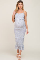 woman wearing a light blue floral maternity dress with ruffle details and a visible baby bump