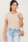 woman wearing a beige short sleeve t-shirt and light wash denim jeans with a matching crossbody bag