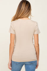 woman wearing a beige short sleeve maternity top, viewed from the back, paired with denim jeans