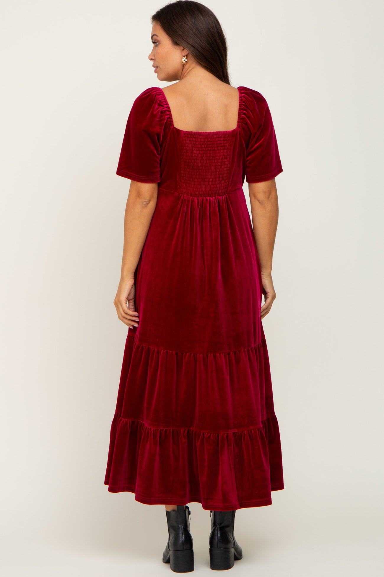 woman wearing a burgundy velvet tiered midi dress with short sleeves and smocked back detail