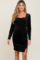 woman wearing a long sleeve black velvet maternity dress with a square neckline and side slit