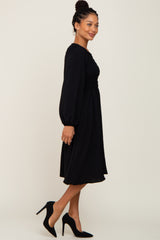 woman wearing a long sleeve black smocked midi dress and black high heel pumps