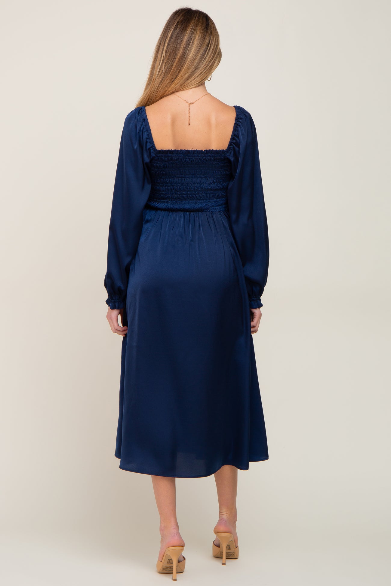 woman wearing a navy blue maternity dress with a smocked bodice and long sleeves seen from the back