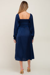 woman wearing a navy blue maternity dress with a smocked bodice and long sleeves seen from the back