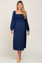 woman wearing a navy blue long sleeve maternity dress with a smocked bodice and a flowing skirt, baby bump visible
