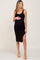 Pregnant woman wearing a black ribbed maternity midi dress with a side slit and tan heels