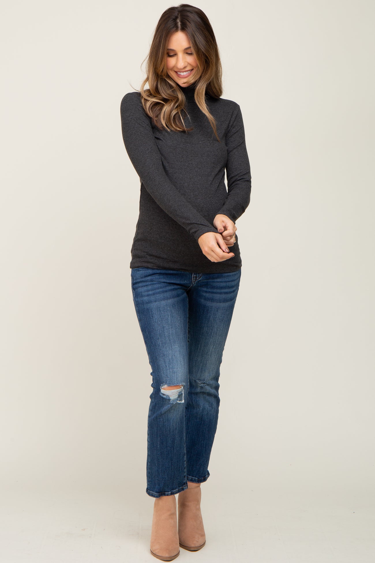 woman wearing a dark gray maternity long sleeve top with jeans and tan ankle boots