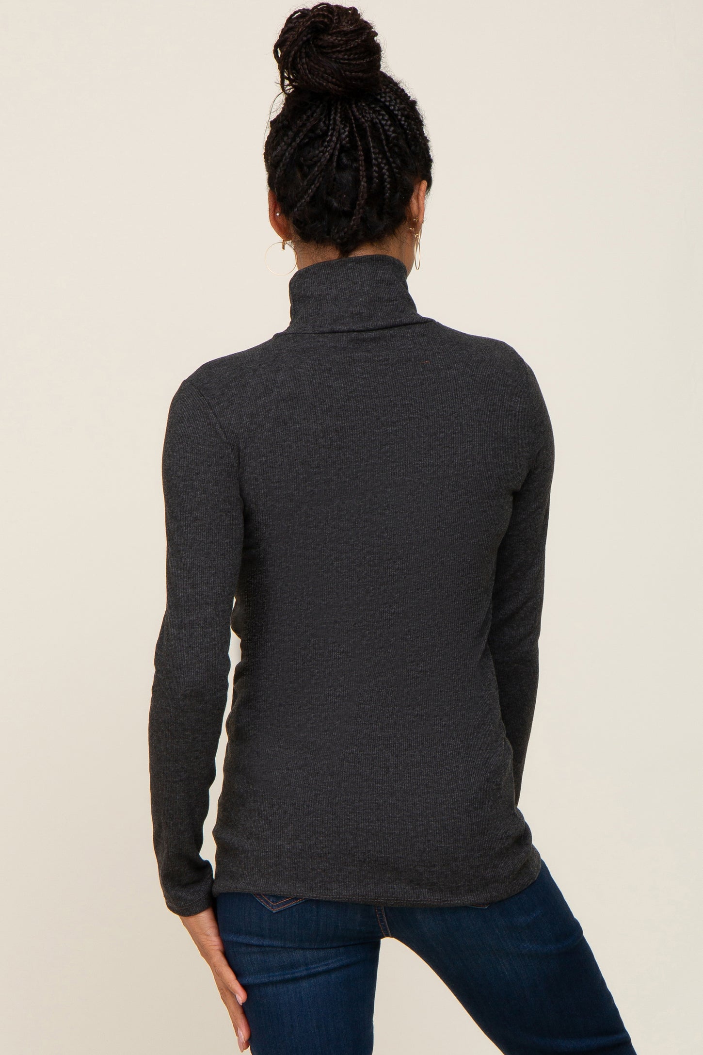 woman wearing a charcoal gray long sleeve turtleneck sweater from the back with dark jeans