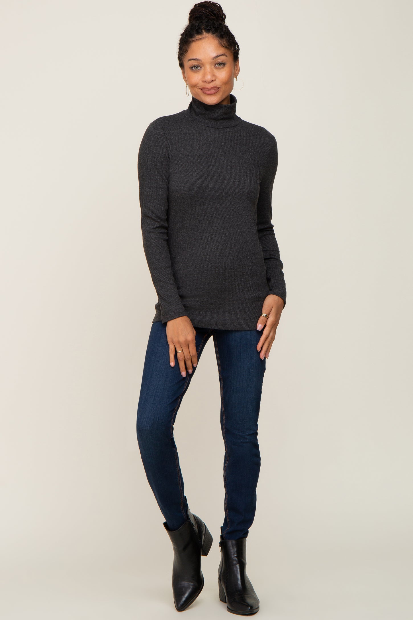 woman wearing a dark gray turtleneck sweater paired with blue skinny jeans and black ankle boots