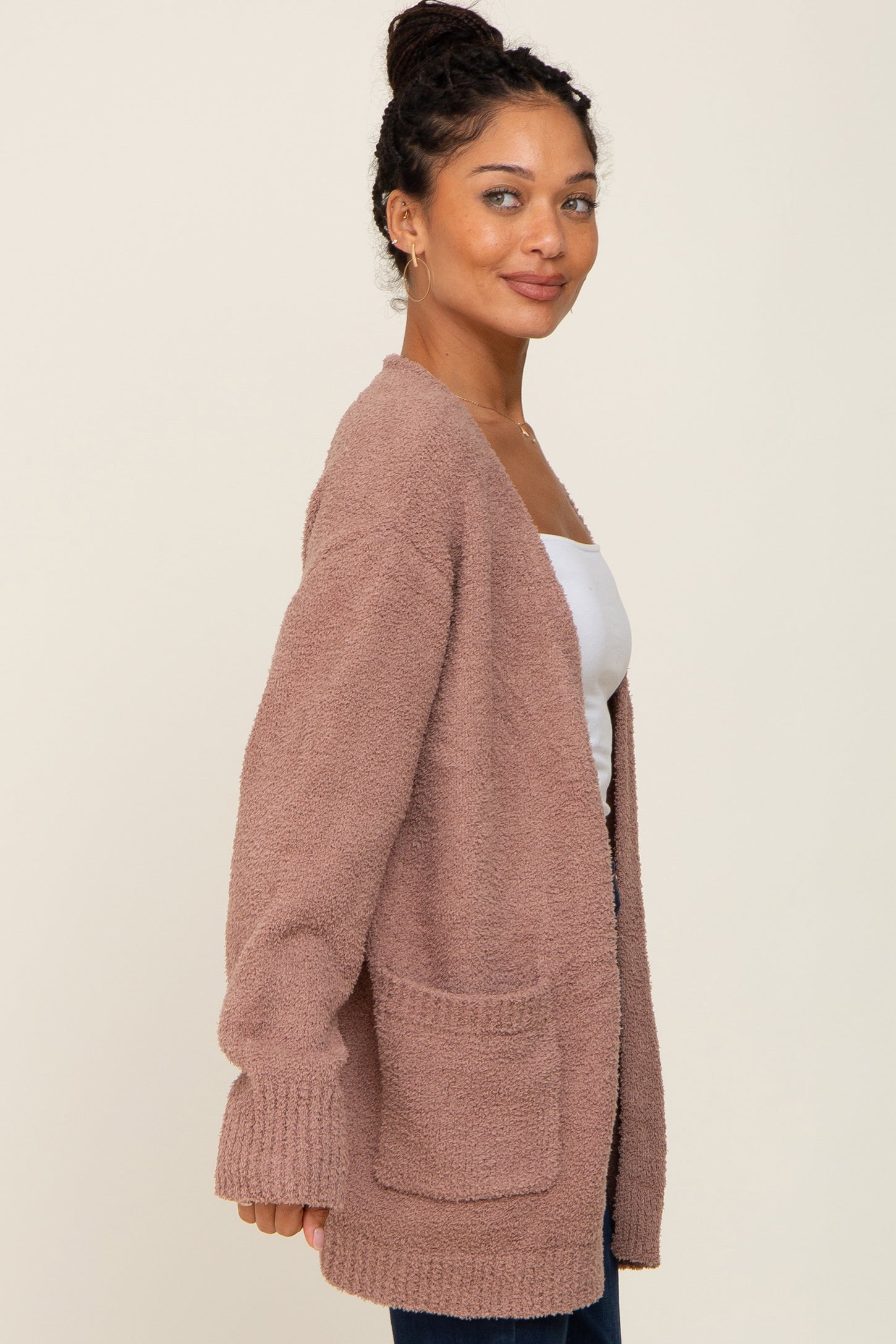 Woman wearing a mauve fuzzy knit cardigan with front pockets over a white top