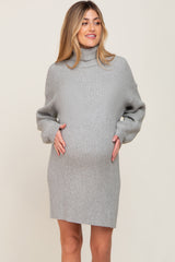 woman wearing a light gray ribbed maternity sweater dress and holding her baby bump