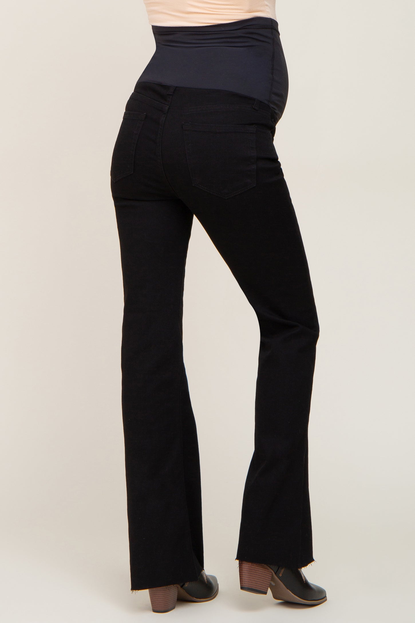 woman wearing black maternity flare jeans with a supportive belly panel and a visible baby bump