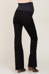 woman wearing black maternity flare jeans with a supportive belly panel and a visible baby bump