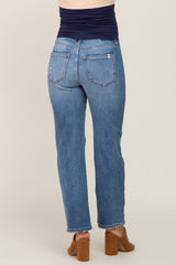 Back view of woman wearing blue straight leg maternity jeans with a navy belly band and brown heeled mules