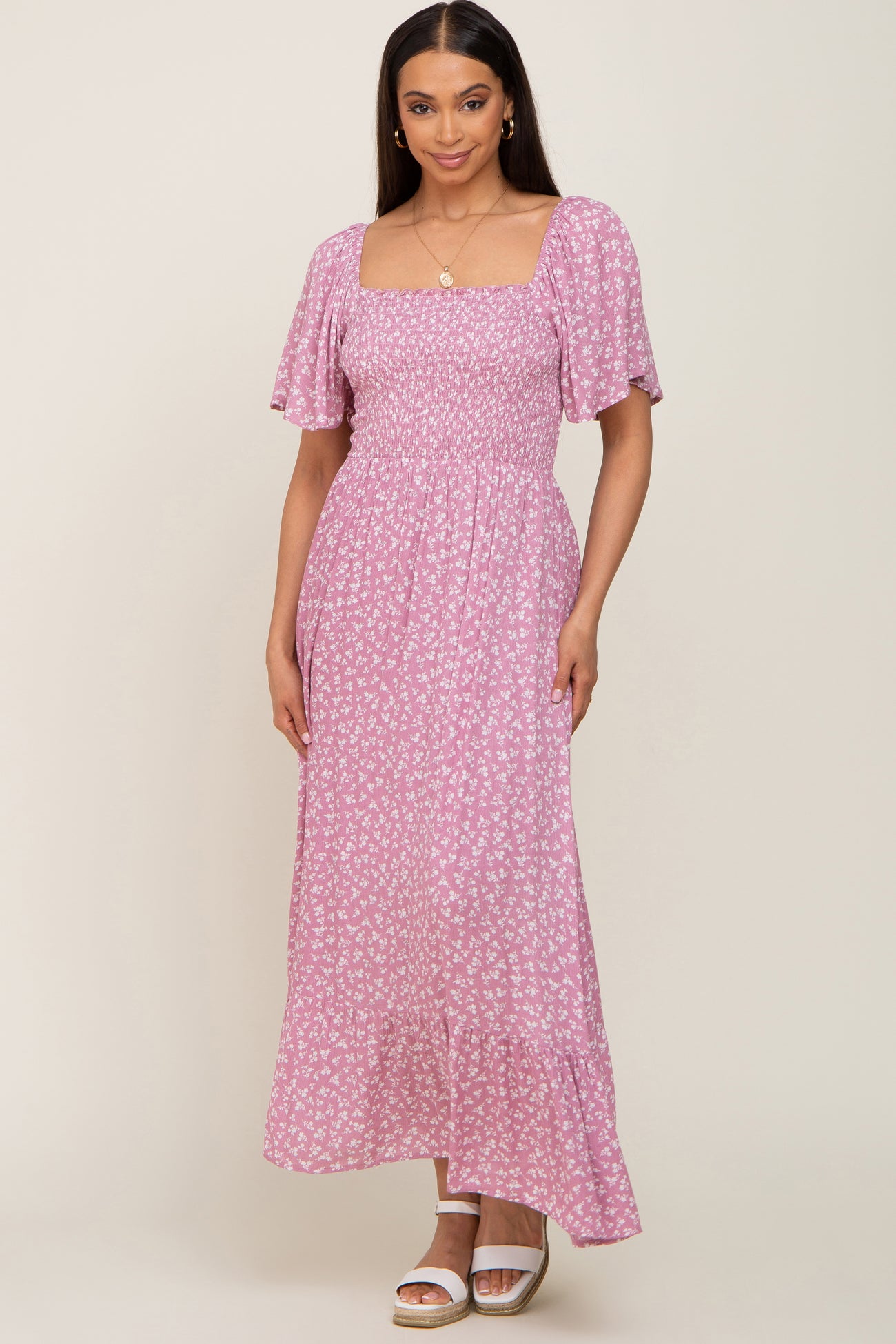 Woman wearing a pink floral smocked maxi dress with flutter sleeves and square neckline