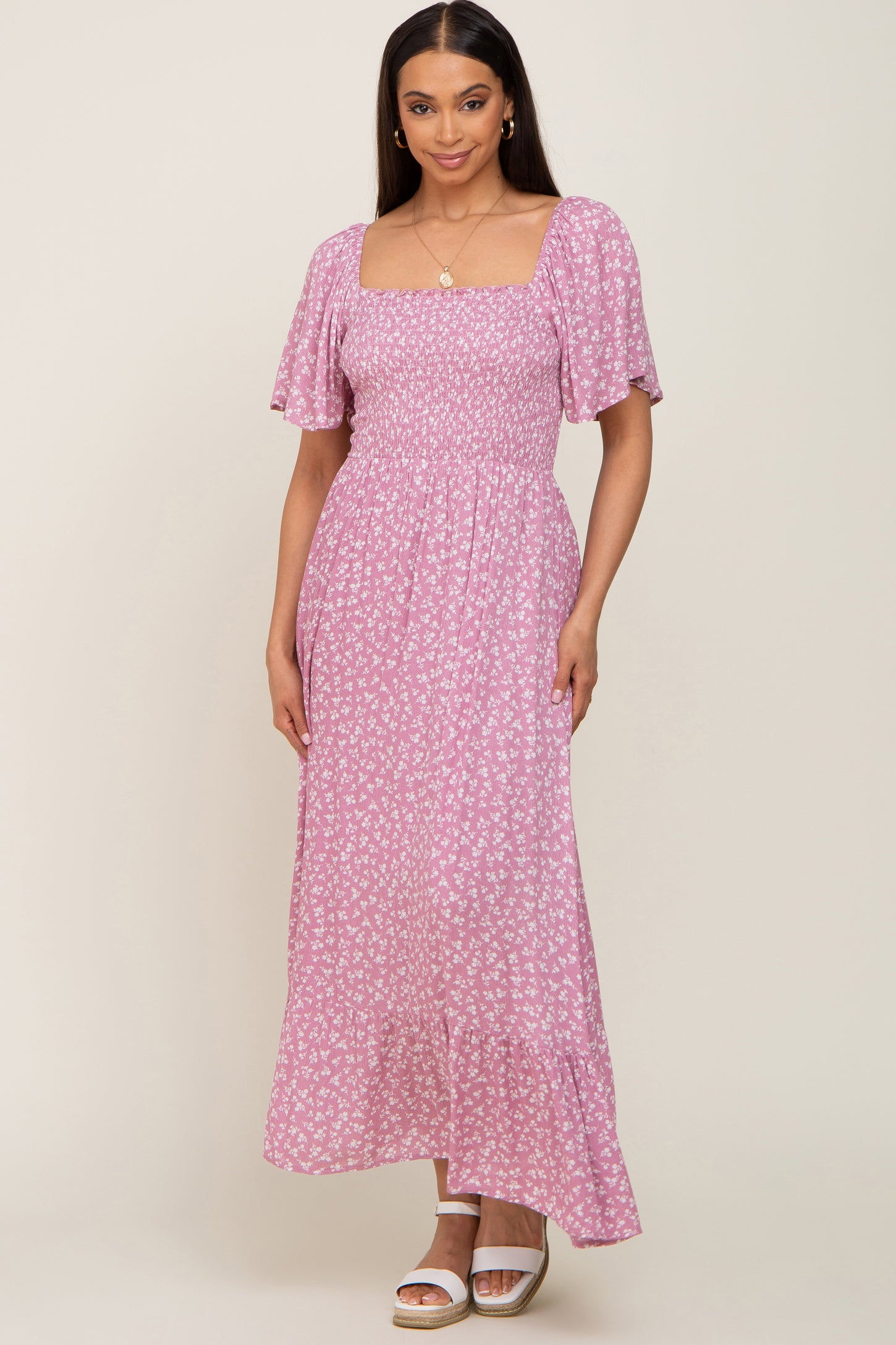 Woman wearing a pink floral smocked maxi dress with flutter sleeves and square neckline