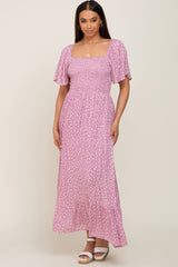 Woman wearing a pink floral smocked maxi dress with flutter sleeves and square neckline
