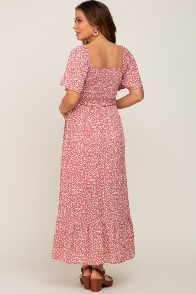 woman wearing a pink floral maternity maxi dress with short sleeves and a fitted bodice, showing a baby bump from the back
