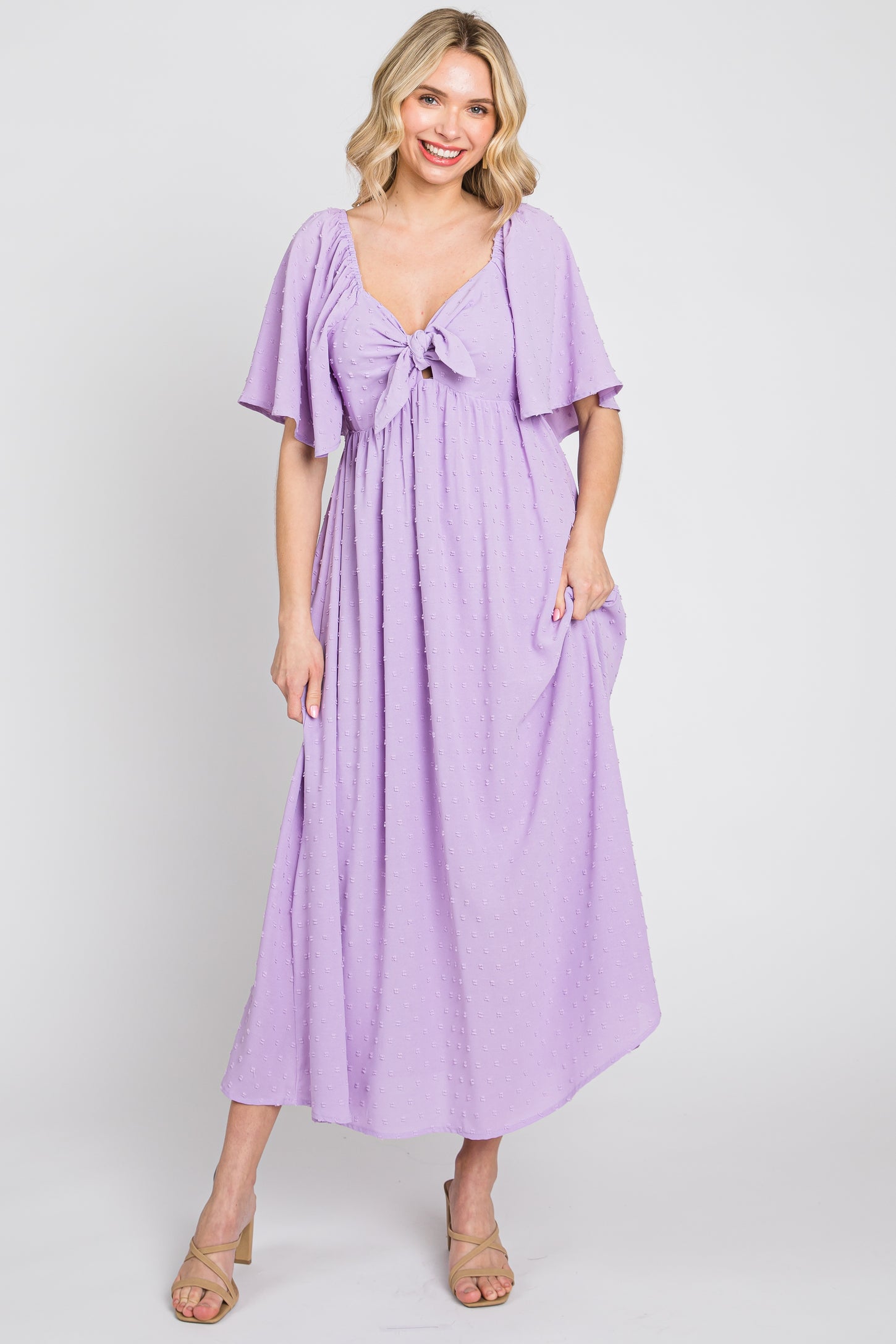 woman wearing a lavender maxi dress with flutter sleeves and a front tie detail