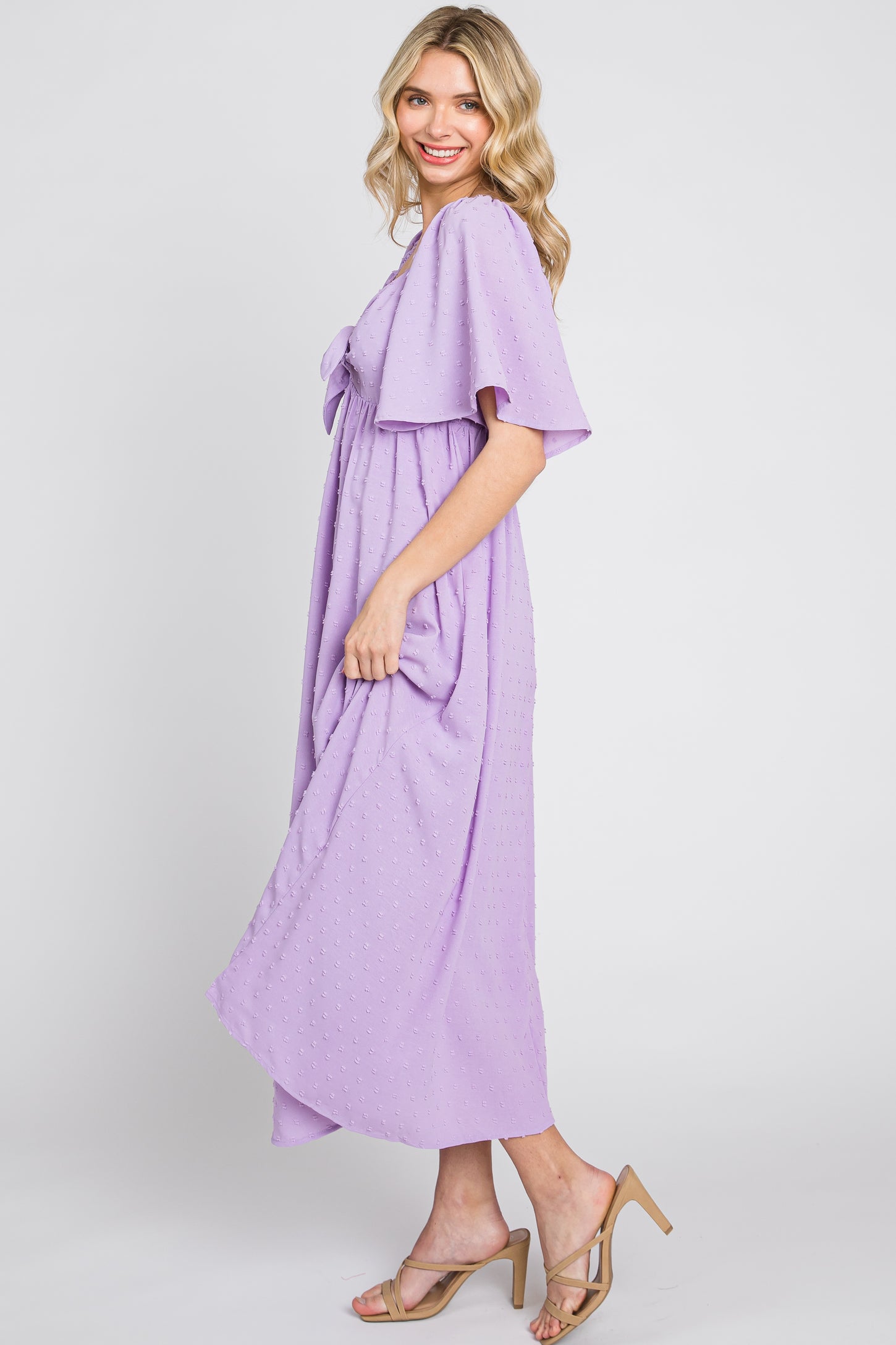 woman wearing a lavender short sleeve maxi dress with a bow detail and a flowing silhouette