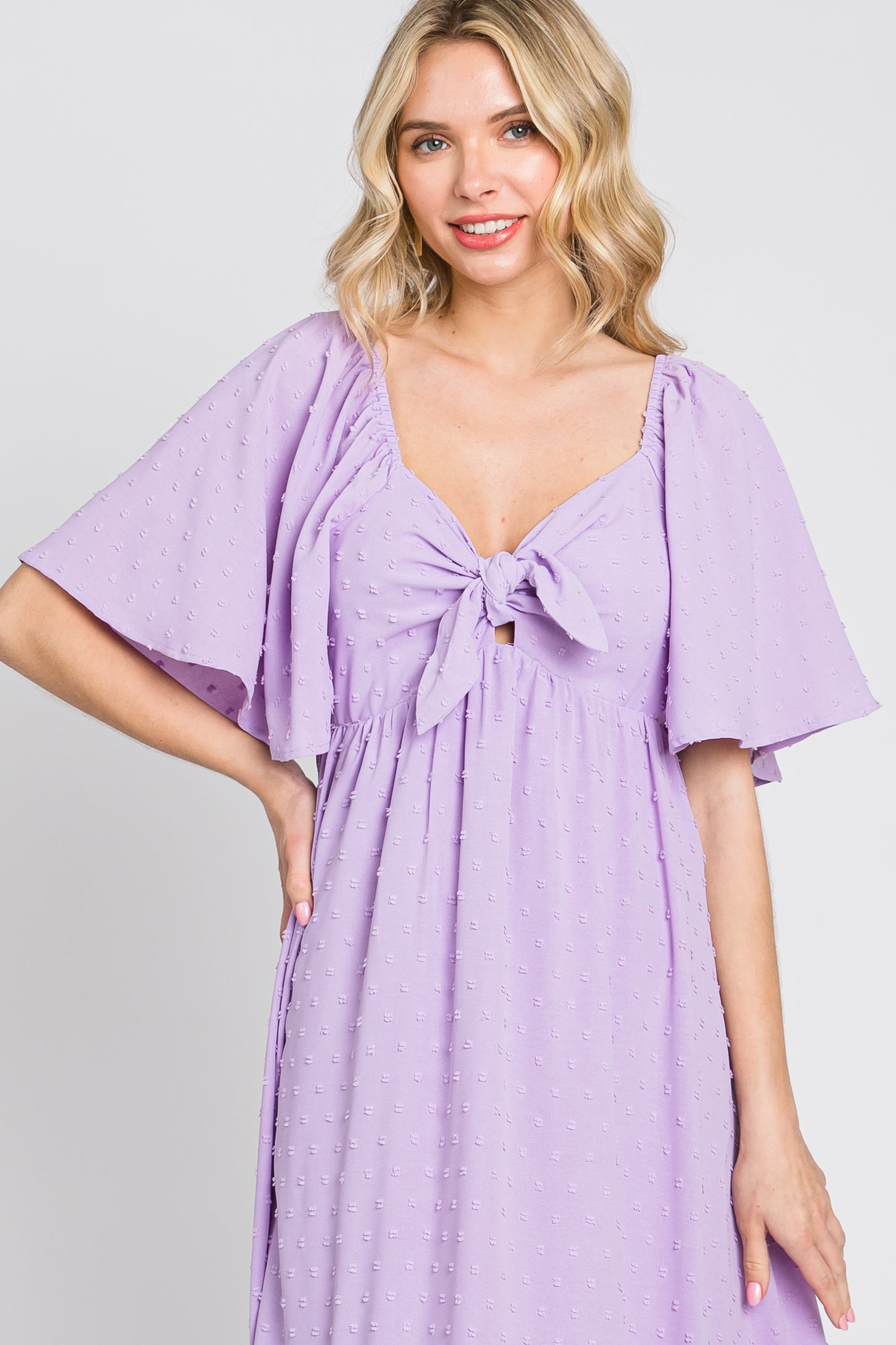 woman wearing a lavender midi dress with short flutter sleeves and a front tie detail
