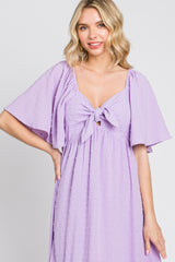 woman wearing a lavender midi dress with short flutter sleeves and a front tie detail