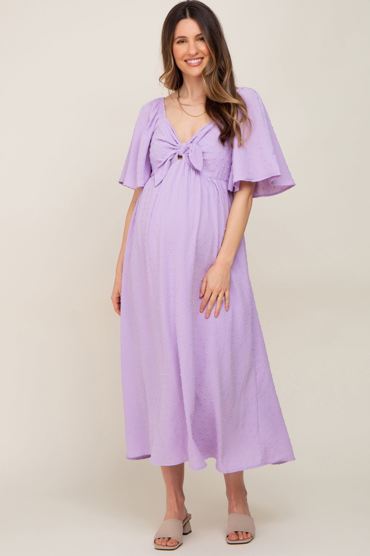 pregnant woman in lavender swiss dot maternity midi dress with tie front and flutter sleeves