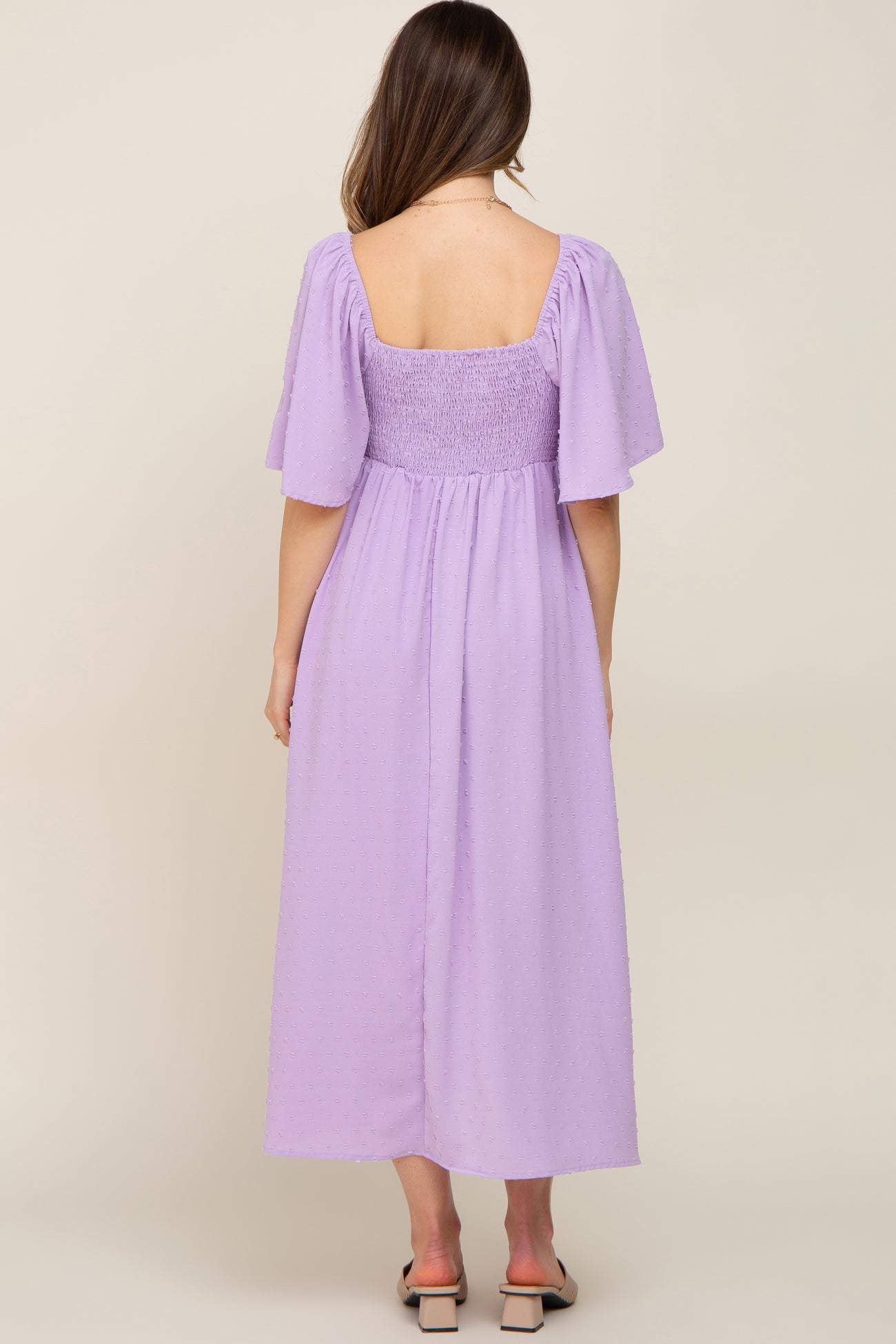 woman wearing a lavender maternity maxi dress with puff sleeves and a smocked back, showing her baby bump