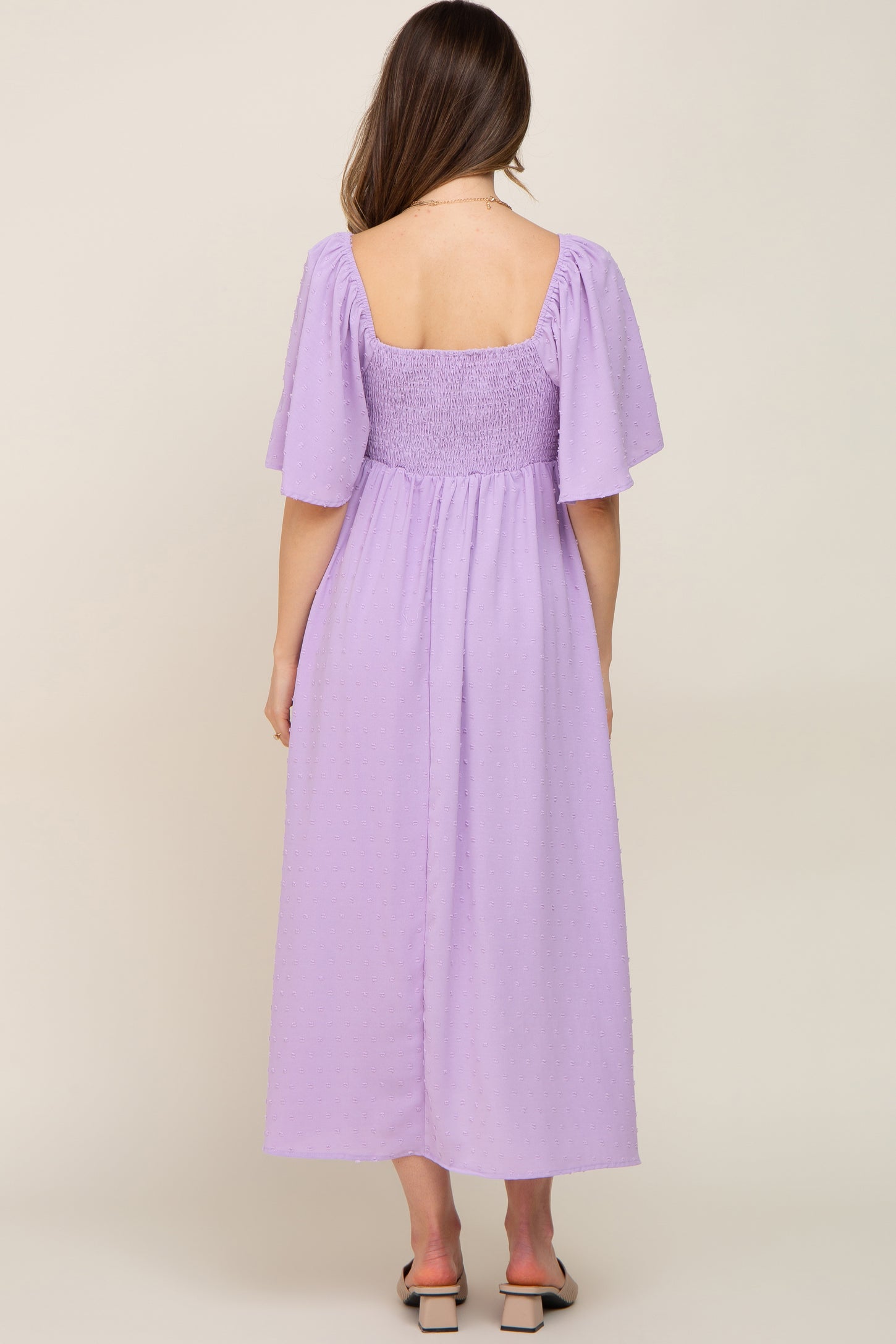 woman wearing a lavender maternity maxi dress with puff sleeves and a smocked back, showing her baby bump