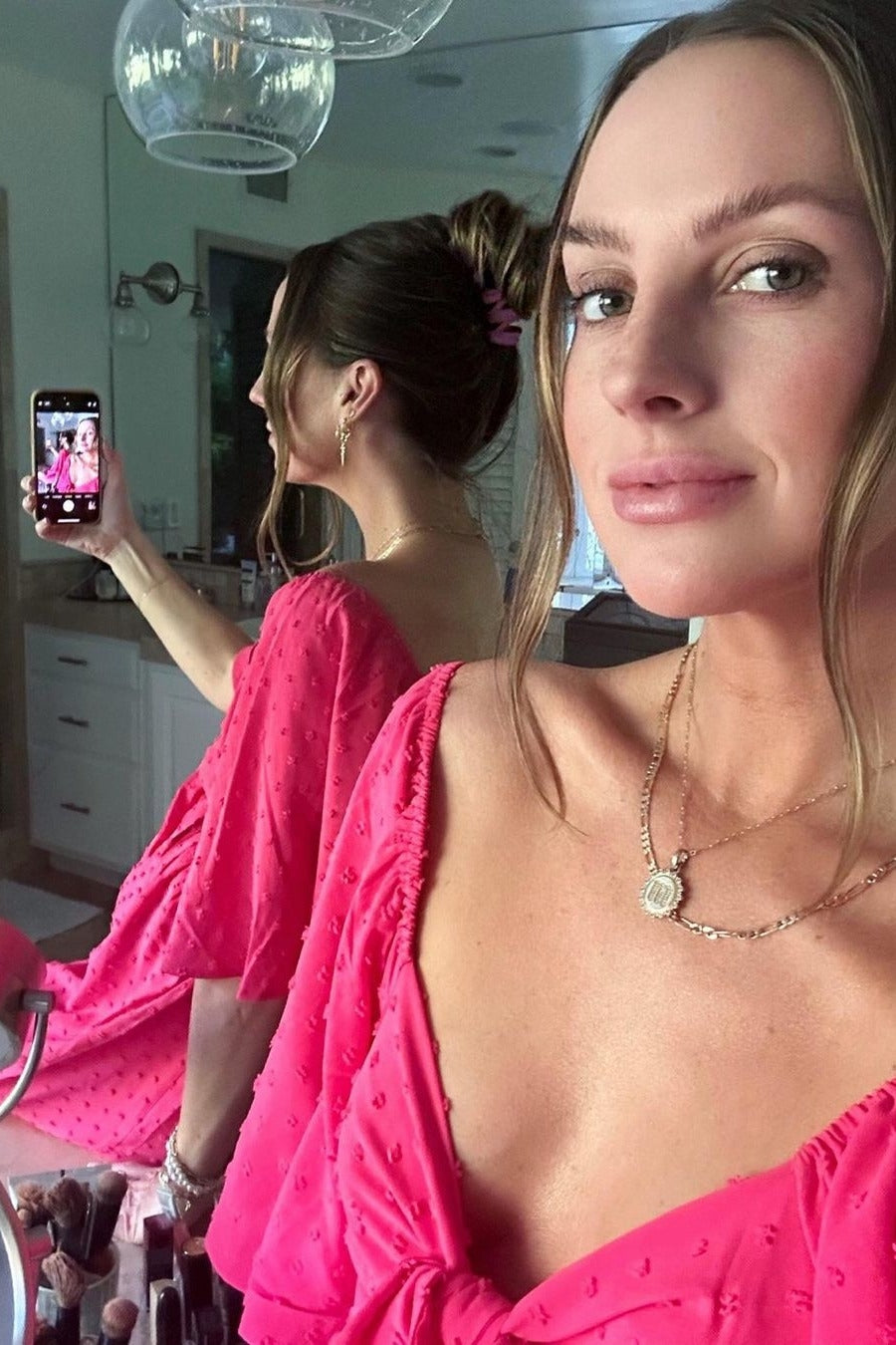 woman wearing a vibrant pink off-the-shoulder top with textured detailing, posing in front of a mirror