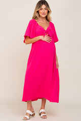 woman wearing a hot pink maternity dress with a tie front and short flutter sleeves, showing her baby bump