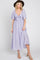 woman wearing a lavender midi dress with flutter sleeves and a knotted front, paired with a wide-brimmed hat and heels