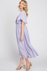 woman wearing a lavender maxi dress with flutter sleeves and a tie waist, standing sideways with a smile