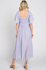 woman wearing a lavender midi dress with short flutter sleeves and a smocked back, seen from the back
