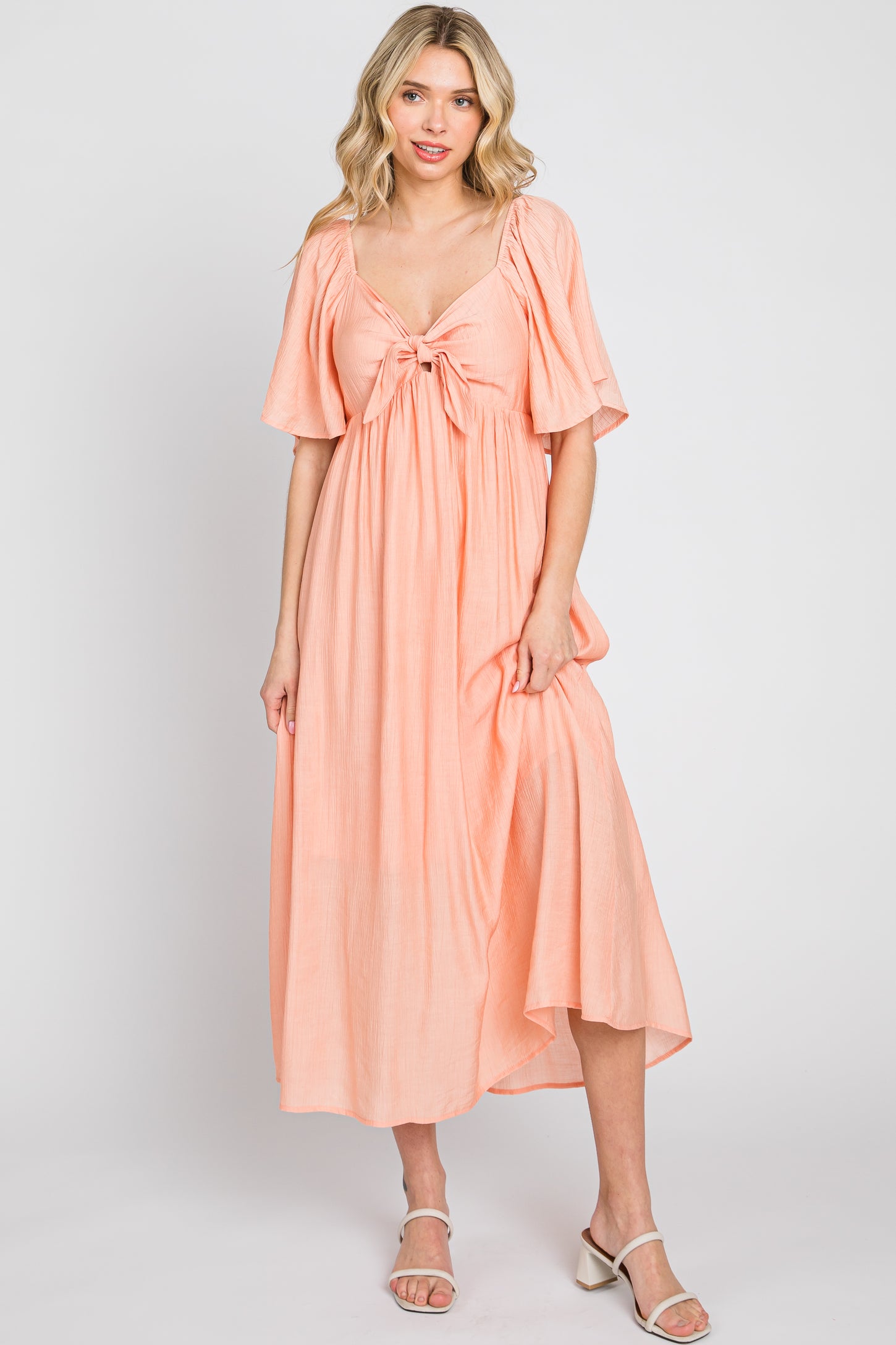 woman wearing a peach maxi dress with short sleeves and a front tie detail