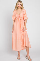 woman wearing a peach maxi dress with short sleeves and a front tie detail