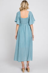 woman wearing a light blue maxi dress with short flutter sleeves and a smocked back