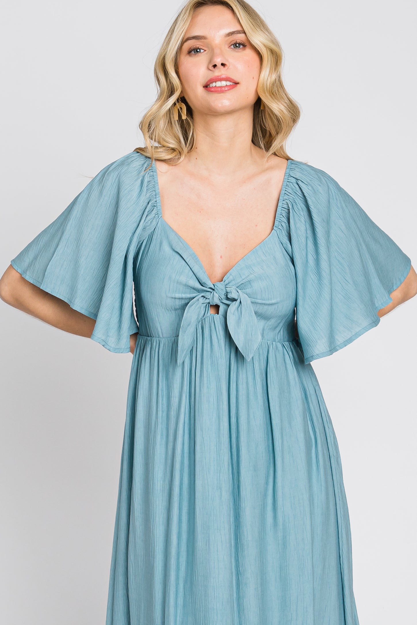 woman wearing a light blue maxi dress with flutter sleeves and a tied front detail