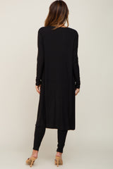 woman wearing a black long sleeve ribbed duster cardigan with side slits and matching leggings, view from the back