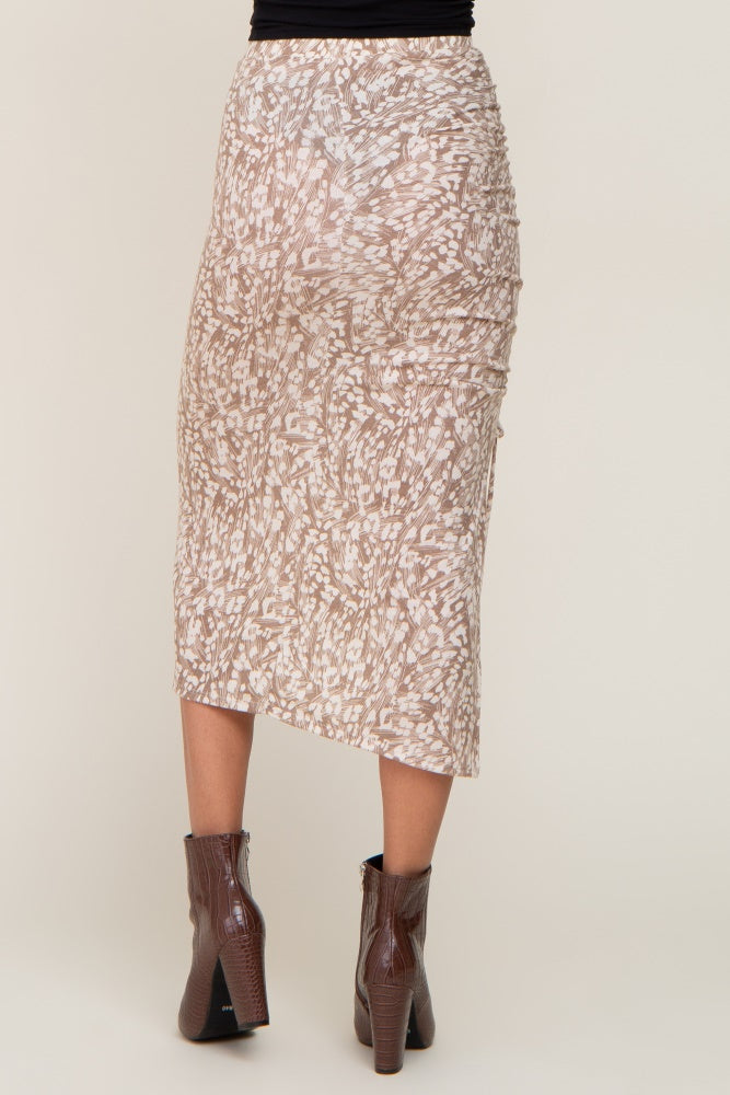 woman wearing a beige patterned midi skirt with a high-low hem and ruched detailing, paired with brown ankle boots